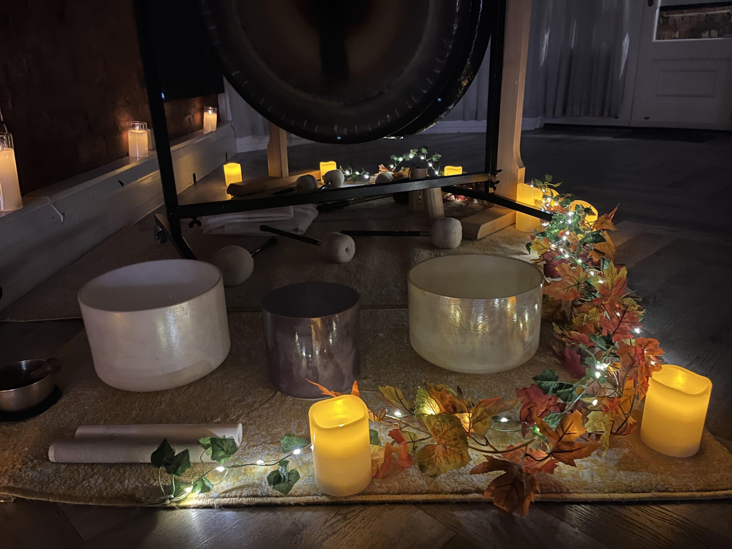 Image of sound bowls surrounded by candles and leaves for Autumn sound healing sessions