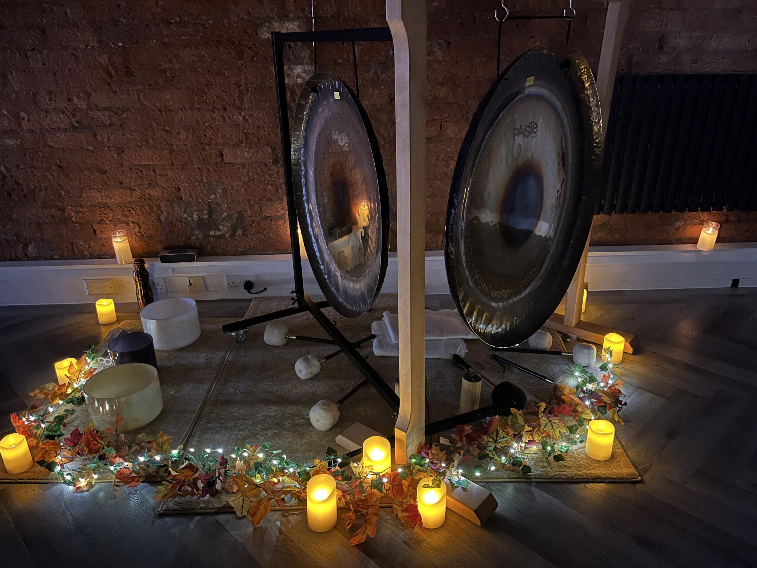 Image of gong surrounded by candles and leaves for Autumn sound healing sessions